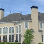 large tan colored custom home sitting beneath blue sky with some white clouds