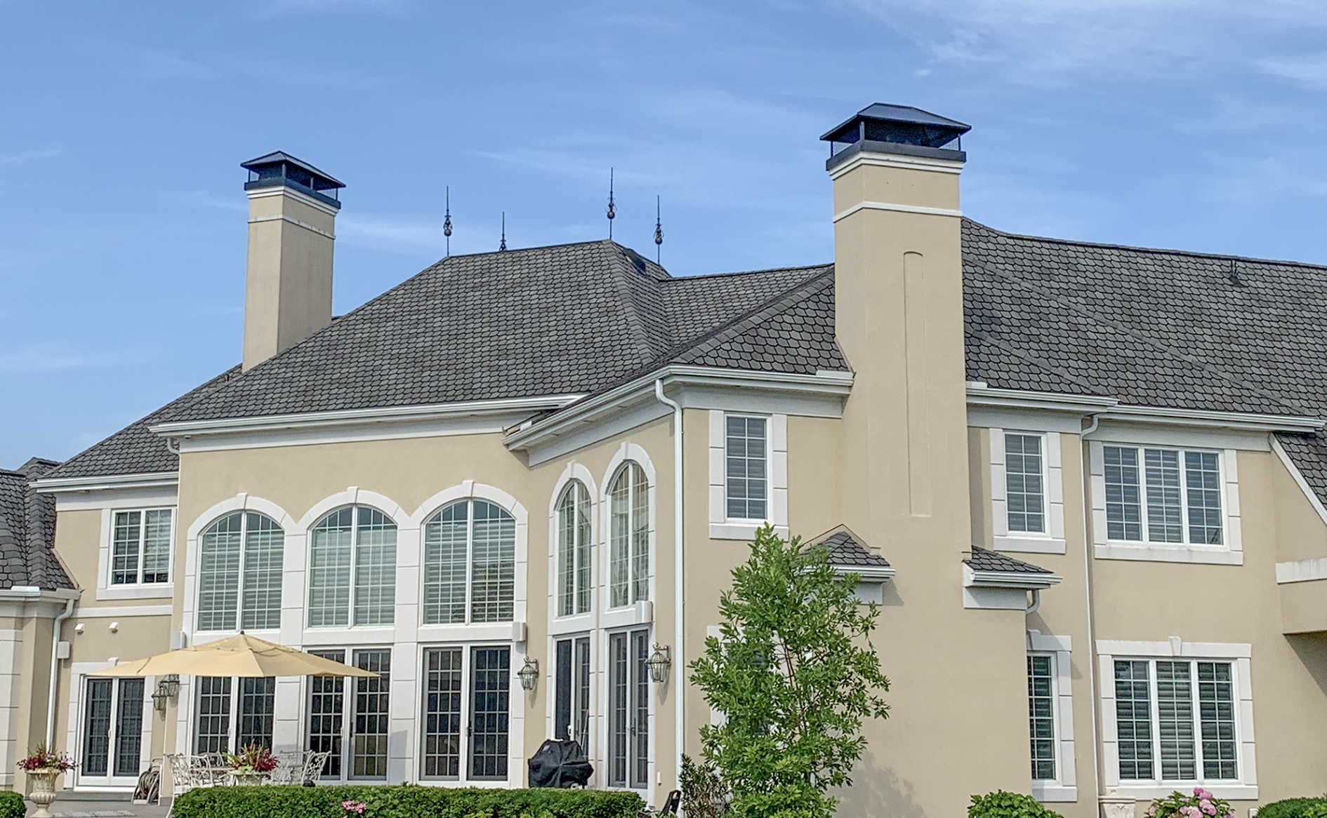 large tan colored custom home sitting beneath blue sky with some white clouds
